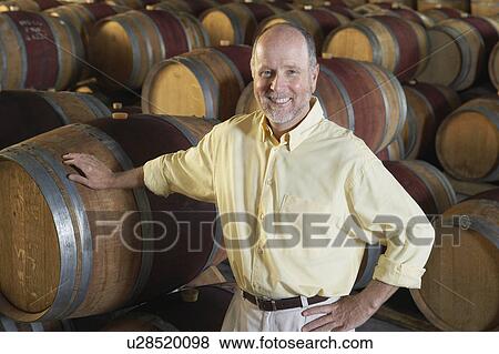 Stock Photo - Man leaning on wine casks. Fotosearch