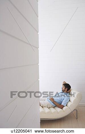 Stock Image - Man lying in reclining chair, half length. Fotosearch