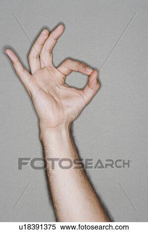 Stock Photography - Man making okay sign, arm raised, close up on hand. Fotosearch