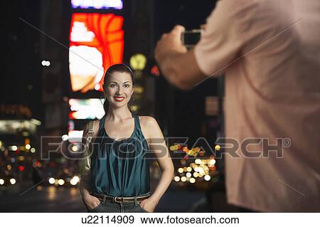 Man Photographing Elegant Woman in Times Square, at night View Large Photo Image Stock Photo - Man Photographing Elegant Woman in Times Square, at night. Fotosearch