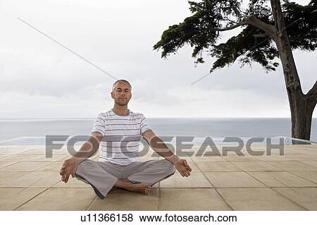 Man sitting in yoga position on terrace by infinity pool View Large Photo Image Stock Photo - Man sitting in yoga position on terrace by infinity pool. Fotosearch