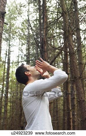Stock Photo - Man standing alone in woods yelling. Fotosearch