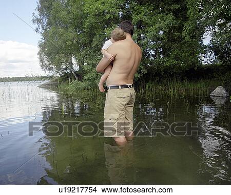 Man Standing in Lake Holding Son View Large Photo Image Picture - Man Standing in Lake Holding Son. Fotosearch