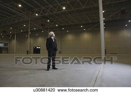 Man stands with hands in pockets in empty warehouse View Large Photo Image Stock Image - Man stands with hands in pockets in empty warehouse. Fotosearch