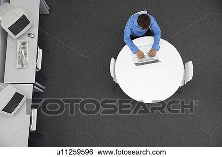 Stock Photograph - Man Using Laptop in computer room, overhead view. Fotosearch