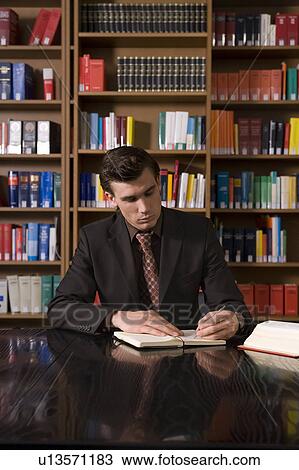 Man wearing suit writing at desk in library View Large Photo Image Stock Image - Man wearing suit writing at desk in library. Fotosearch