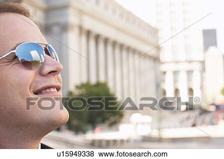Stock Photo - Man wearing sunglasses, smiling, outdoors. Fotosearch