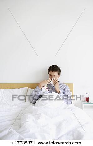 Man with cold in bed blowing nose View Large Photo Image Stock Image - Man with cold in bed blowing nose. Fotosearch