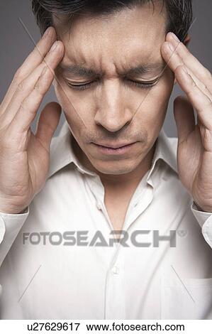 Stock Photo - Man with fingers pressed to forehead, close-up. Fotosearch