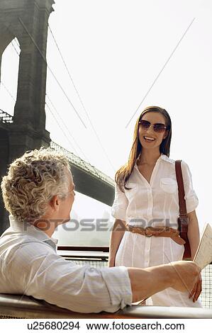 Man with newspaper talking to woman outdoors View Large Photo Image Picture - Man with newspaper talking to woman outdoors. Fotosearch