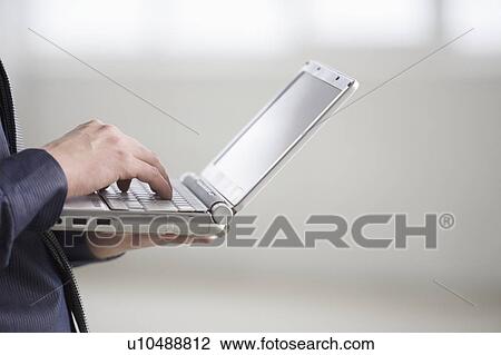 Man works on laptop, standing up View Large Photo Image Stock Image - Man works on laptop, standing up. Fotosearch