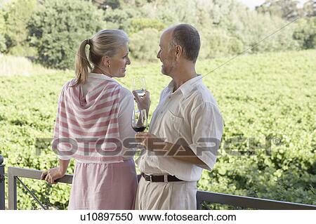 Mature couple on terrace holding wine glasses View Large Photo Image Stock Image - Mature couple on terrace holding wine glasses. Fotosearch