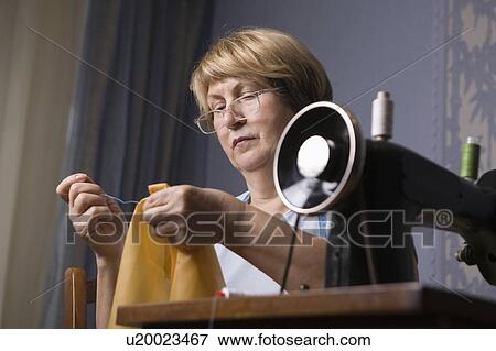 Stock Photo - Mature woman repairing clothes. Fotosearch