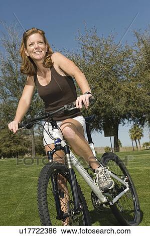 Stock Photograph - Mature woman stands with mountain bike. Fotosearch