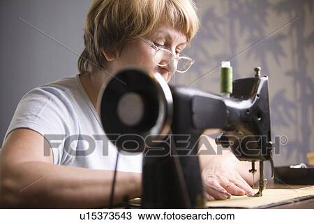Mature woman works at sewing machine View Large Photo Image Stock Image - Mature woman works at sewing machine. Fotosearch