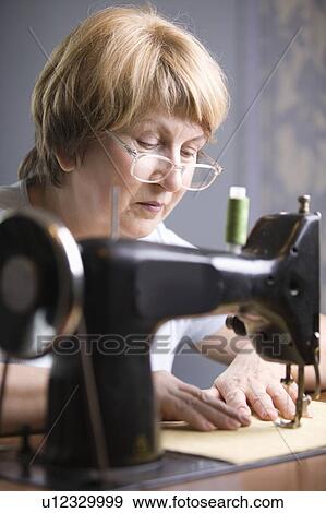 Mature woman works at sewing machine View Large Photo Image Stock Photo - Mature woman works at sewing machine. Fotosearch