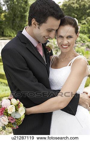 Mid adult bride and groom in garden, embracing View Large Photo Image Stock Photo - Mid adult bride and groom in garden, embracing. Fotosearch