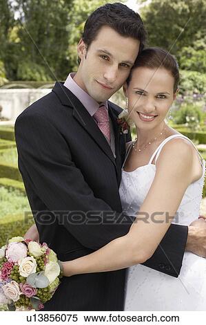 Mid adult bride and groom in garden, embracing View Large Photo Image Stock Photography - Mid adult bride and groom in garden, embracing. Fotosearch