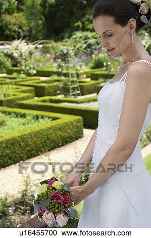 Mid adult bride in garden, holding bouquet, side view View Large Photo Image Stock Image - Mid adult bride in garden, holding bouquet, side view. Fotosearch
