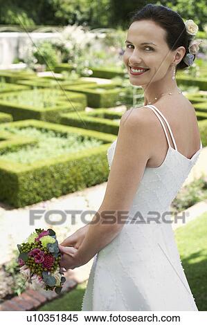 Mid adult bride in garden, holding bouquet, smiling View Large Photo Image Stock Photography - Mid adult bride in garden, holding bouquet, smiling. Fotosearch