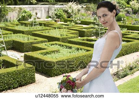 Mid adult bride in garden, holding bouquet, side view View Large Photo Image Stock Photography - Mid adult bride in garden, holding bouquet, side view. Fotosearch
