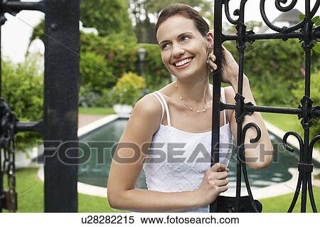 Stock Photography - Mid adult bride, leaning on gate, looking away, portrait. Fotosearch