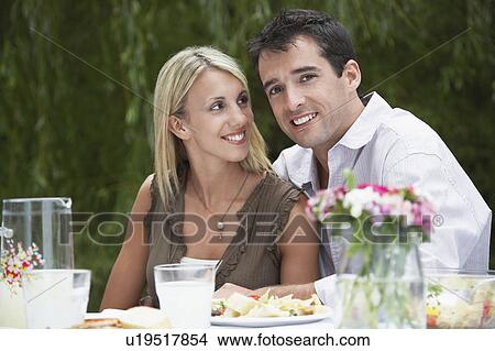 Picture - Mid-adult couple dining at table in garden. Fotosearch