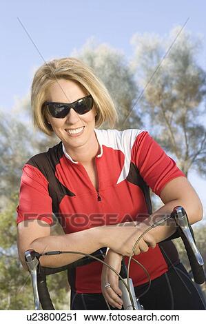 Mid adult cyclist in red cycling top leans on bicycle handlebars View Large Photo Image Stock Image - Mid adult cyclist in red cycling top leans on bicycle handlebars. Fotosearch