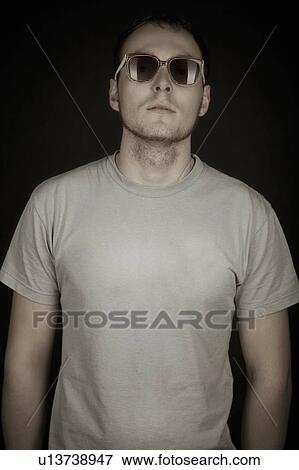 Stock Photo - Mid adult man stands in sunglasses. Fotosearch