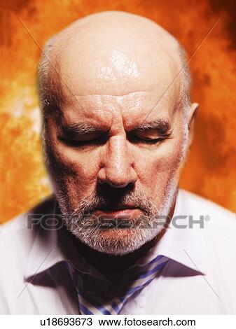 Stock Image - Middle-aged businessman, eyes closed in suffering, close-up. Fotosearch