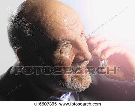 Middle-Aged Businessman looking into bright light, talking on mobile View Large Photo Image Stock Photography - Middle-Aged Businessman looking into bright light, talking on mobile. Fotosearch