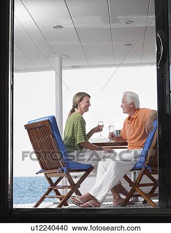 Middle-aged couple drinking wine on yacht, profile, view through door View Large Photo Image Stock Image - Middle-aged couple drinking wine on yacht, profile, view through door. Fotosearch