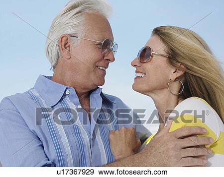 Middle-aged couple embracing and looking in eyes against sky View Large Photo Image Stock Photo - Middle-aged couple embracing and looking in eyes against sky. Fotosearch