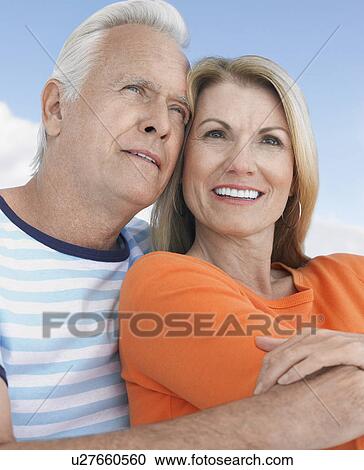 Stock Image - Middle-aged couple outdoors, embracing and smiling. Fotosearch