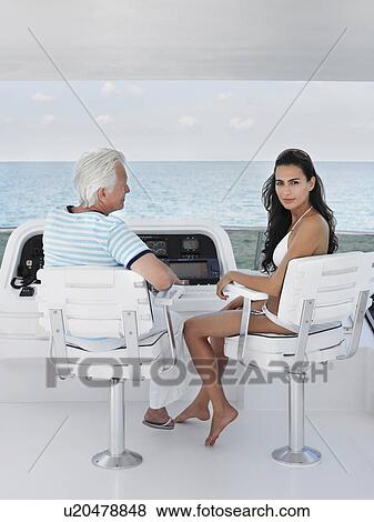Middle-aged man and young woman sitting at helm of yacht View Large Photo Image Stock Photo - Middle-aged man and young woman sitting at helm of yacht. Fotosearch