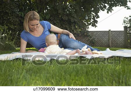 Stock Photo - Mother and baby lying on lawn in garden. Fotosearch