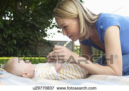 Stock Photo - Mother and baby lying on lawn in garden. Fotosearch