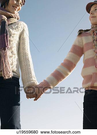 Stock Image - Mother and daughter holding hands, outdoors, low angle view, cropped. Fotosearch