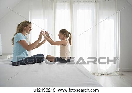 Mother and daughter sitting on bed playing patty cake, side view View Large Photo Image Stock Image - Mother and daughter sitting on bed playing patty cake, side view. Fotosearch