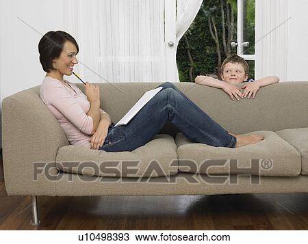Stock Image - Mother and young son by couch. Fotosearch