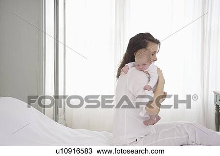 Stock Image - Mother holds two week old newborn baby. Fotosearch
