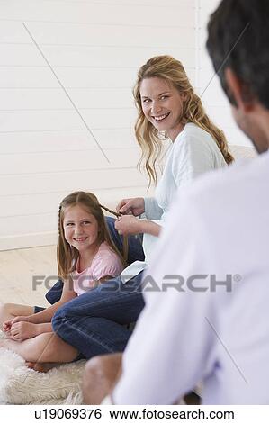 Mother plaiting daughter's hair, looking at father View Large Photo Image Stock Photograph - Mother plaiting daughter's hair, looking at father. Fotosearch