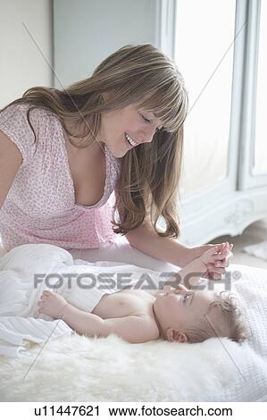 Mother sits playing with baby boy View Large Photo Image Stock Image - Mother sits playing with baby boy. Fotosearch