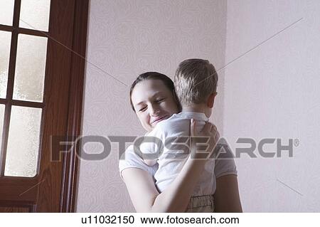Mother smiles with happiness while hugging her son View Large Photo Image Stock Image - Mother smiles with happiness while hugging her son. Fotosearch