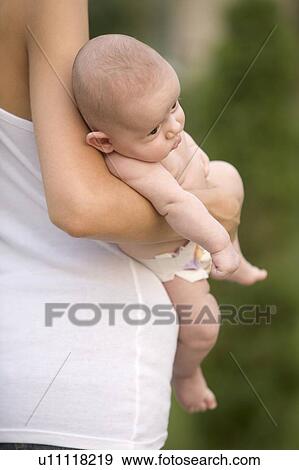 Stock Photo - Mother stands holding 2 month old infant son. Fotosearch