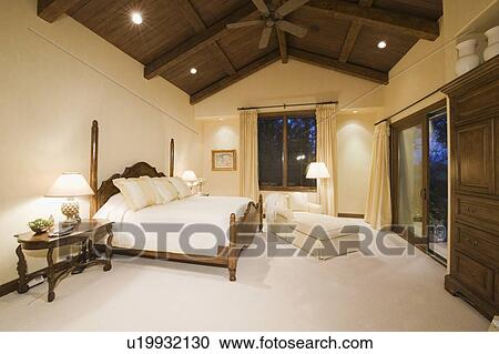 Stock Image - Neutral bedroom with high wooden ceiling. Fotosearch