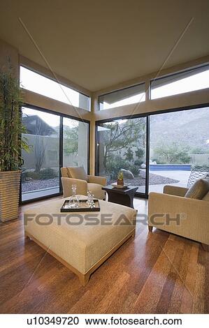 Stock Image - Neutrally upholstered furniture in room corner with floor to ceiling windows. Fotosearch
