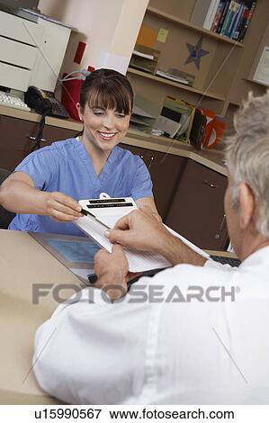 Nurse and doctor doing paperwork in doctor's office View Large Photo Image Stock Photo - Nurse and doctor doing paperwork in doctor's office. Fotosearch