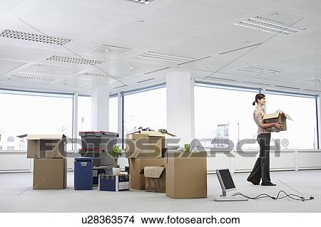 Office worker carrying carton near cartons and equipment on floor of empty office space View Large Photo Image Picture - Office worker carrying carton near cartons and equipment on floor of empty office space. Fotosearch
