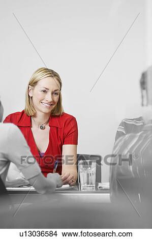 Picture - Office worker sitting with colleagues at conference table (isolated colour). Fotosearch